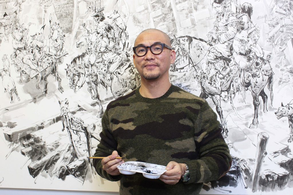 Photo of Kim Jung Gi in front of his art